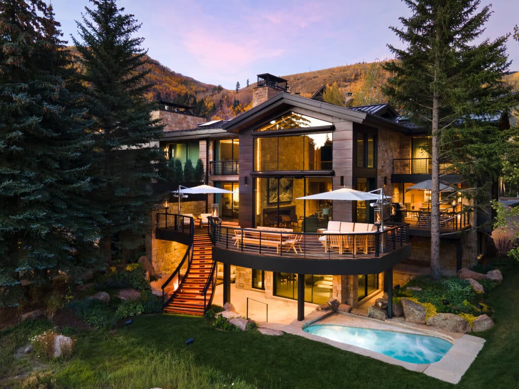 The exterior of a three story home with sunset on the mountains in the background